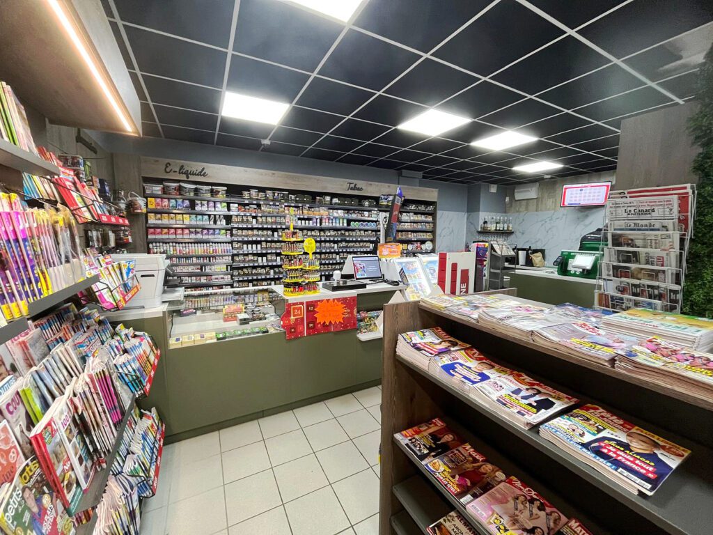 Vue générale de l'agencement du tabac presse Le Chiniacus à Cheny par Sudexpo : comptoir vert kaki, mur tabac et e-liquide, gondoles presse, mur végétal et plafond noir suspendu